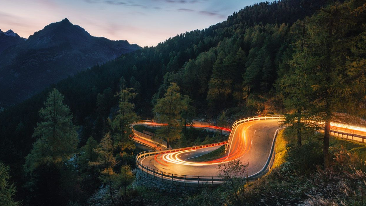 Eine Serpentinenstraße in den bewaldeten Bergen zu Dämmerung.