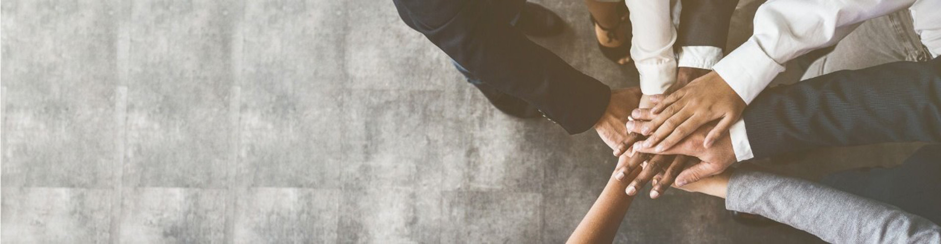Das Bild zeigt eine Menschengruppe ihre Hände vereint aufeinanderlegend.