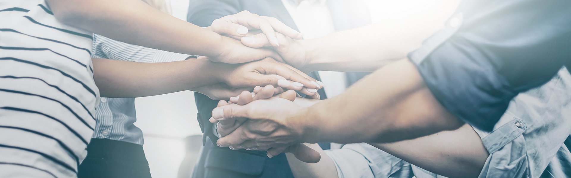 Eine Gruppe an Menschen legen ihre Hände vereint aufeinander.