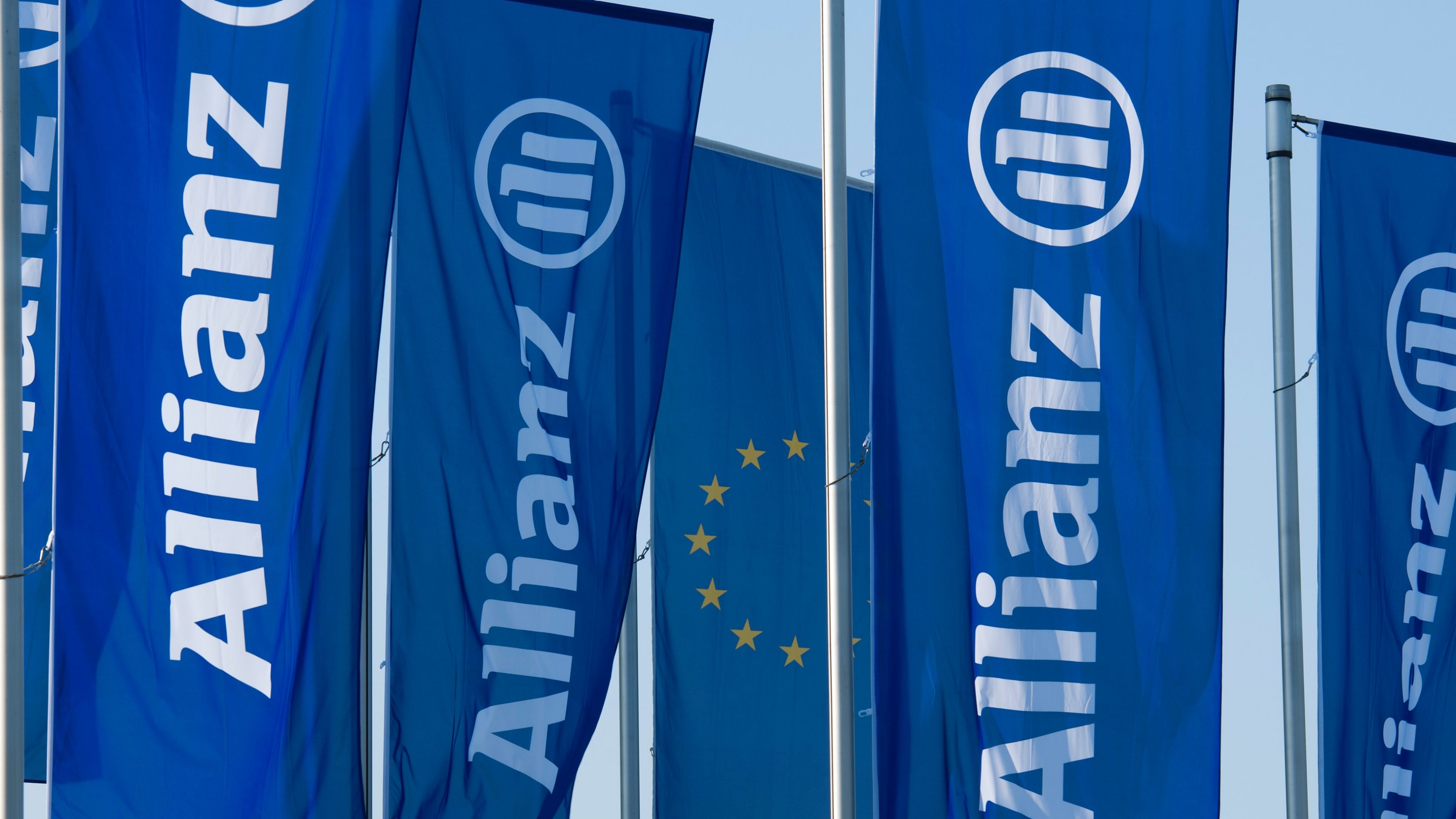 Mehrere blaue Flaggen mit dem Allianz Logo wehen im Wind.