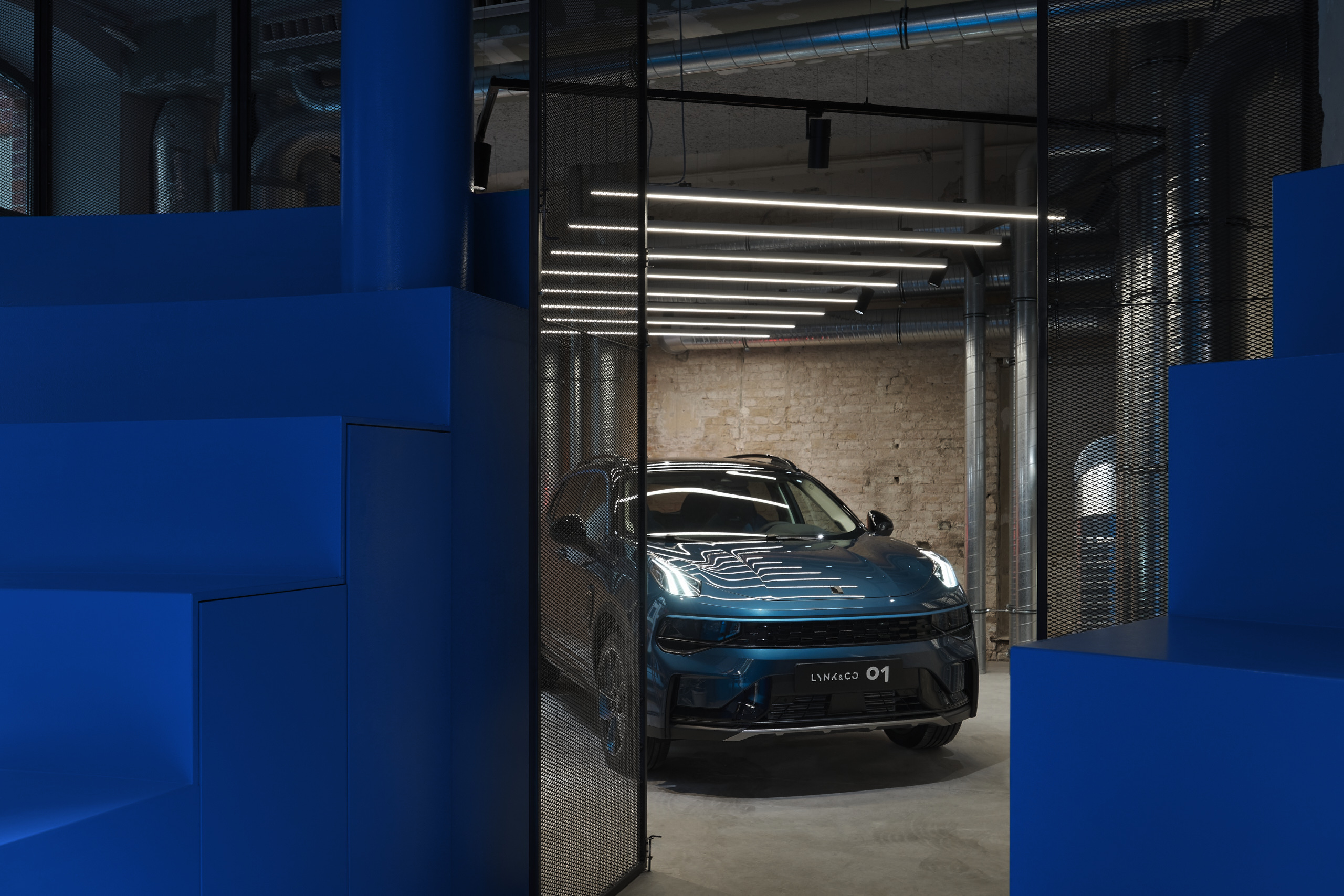 Ein dunkelblaues Auto fährt aus einer beleuchtete Garage mit blauen Toren.
