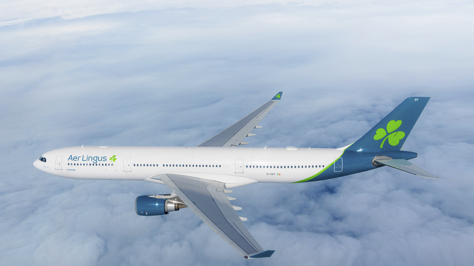 Ein weißer Aer Lingus Airbus A330-300 mit grünem Kleeblatt-Logo fliegt über den Wolken.
