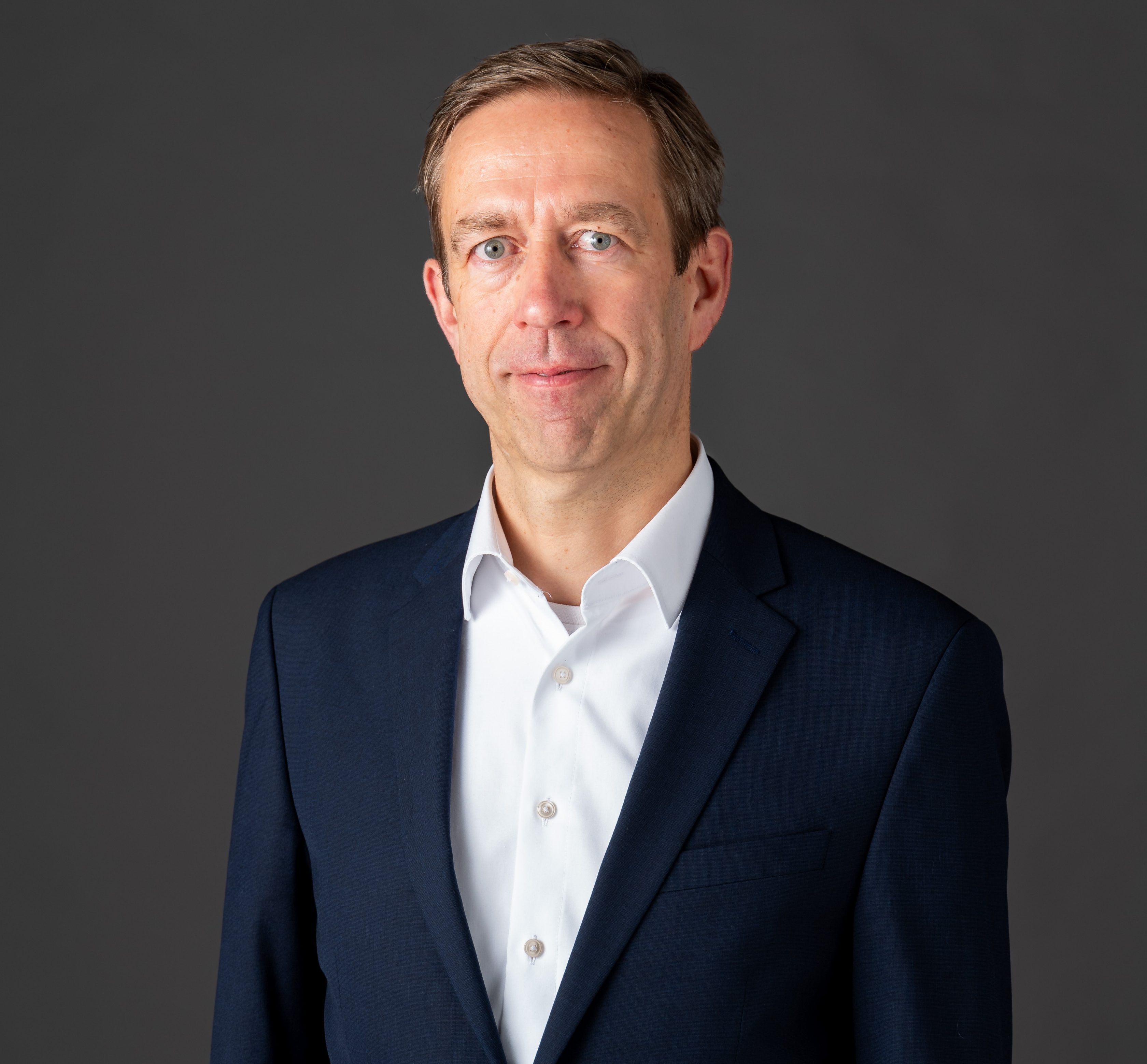 Michael Buttstedt, Chief Financial Officer von Allianz Partners: Ein Mann steht vor grauem Hintergrund. Er trägt kurze Haare, ein weißes Hemd und darüber ein Sakko. Michael Buttstedt, Chief Financial Officer von Allianz Partners: Ein Mann steht vor grauem Hintergrund. Er trägt kurze Haare, ein weißes Hemd und darüber ein Sakko.