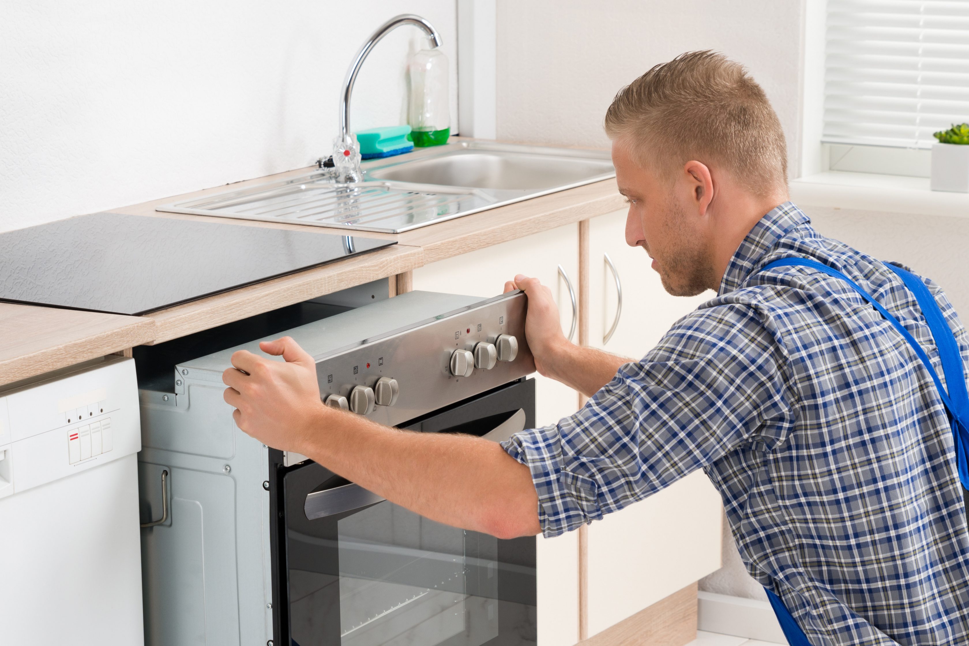Ein Handwerker schiebt einen Backofen in die Küchentheke in einem Haus.