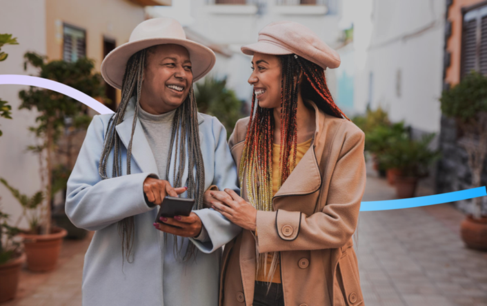 Zwei Frauen unterhalten sich lachend miteinander. Die Frau rechts ist jünger und die Frau links ist älter. 