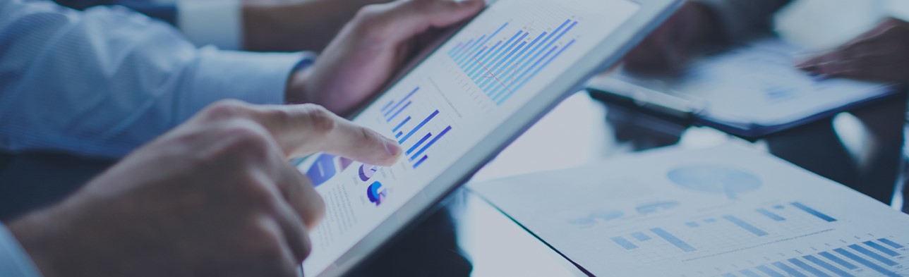 Eine Person zeigt auf ein Balkendiagramm, das auf einem abheftetem Dokument ist.