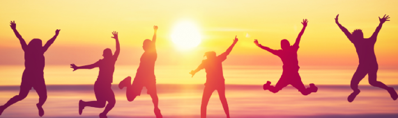 People jumping for joy with the sun setting in the distance