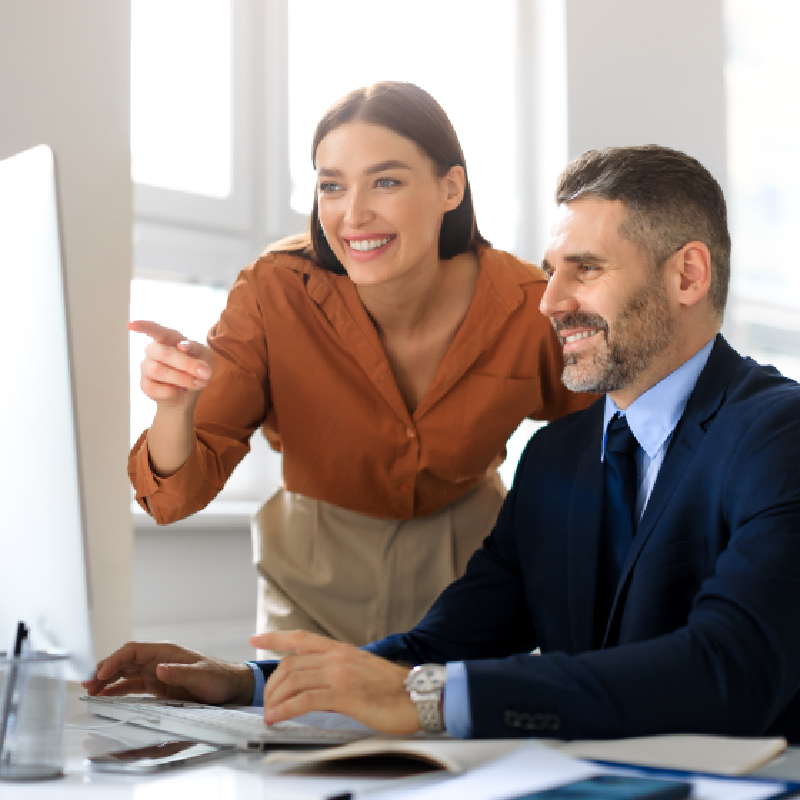A business corporate man and woman smiling at a computer screen