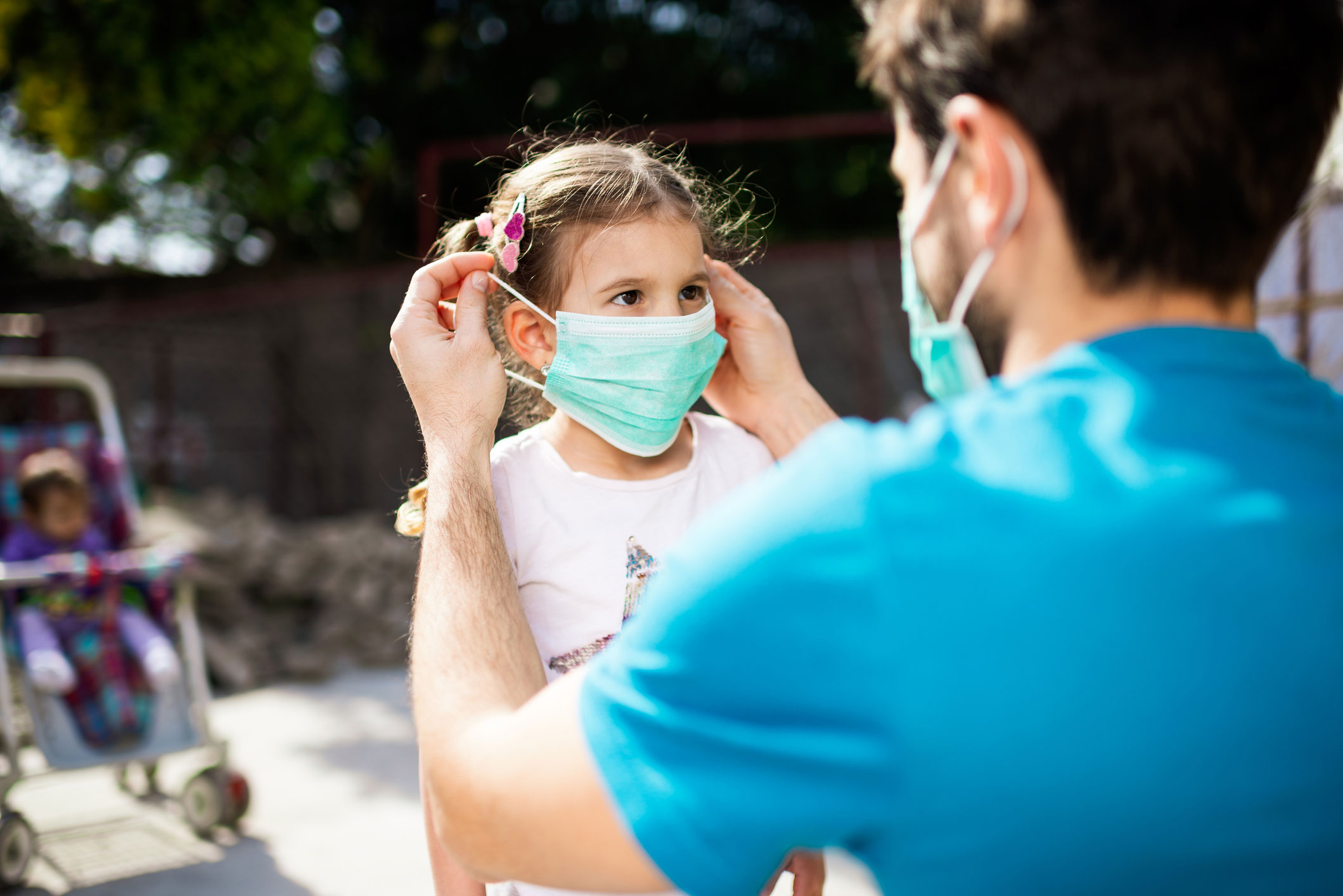 Dad putting a protective mask on his daughter