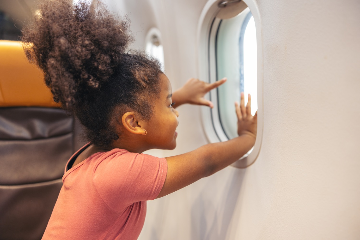Petite fille qui regarde par le hublot d'un avion