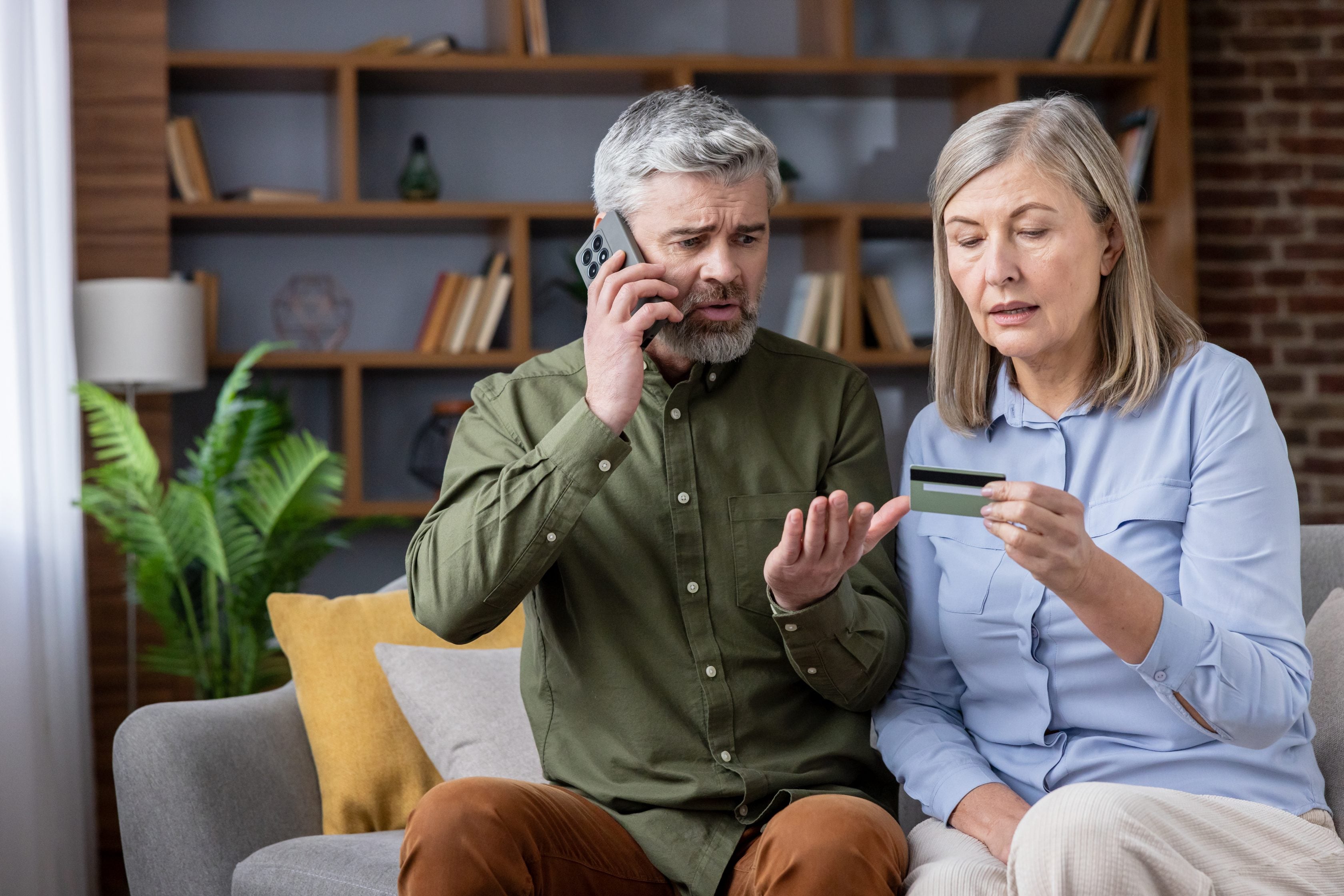 Couple inquiet au téléphone avec leur carte de crédit à la main