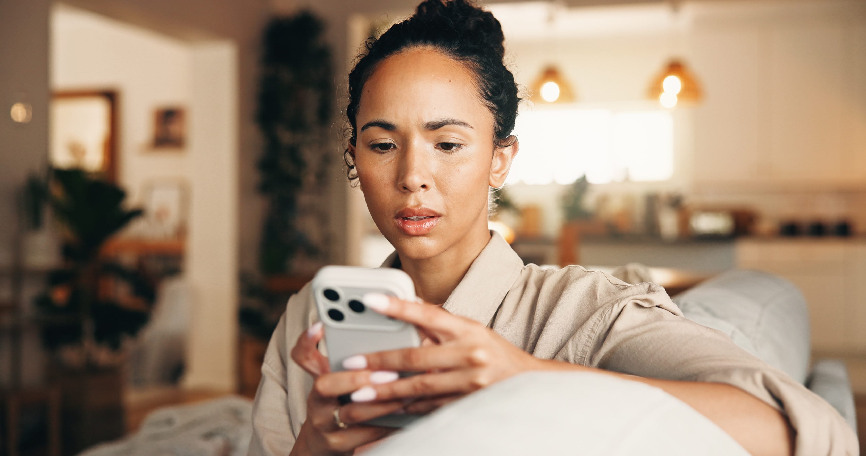 Jeune femme soucieuse chez elle sur son téléphone portable