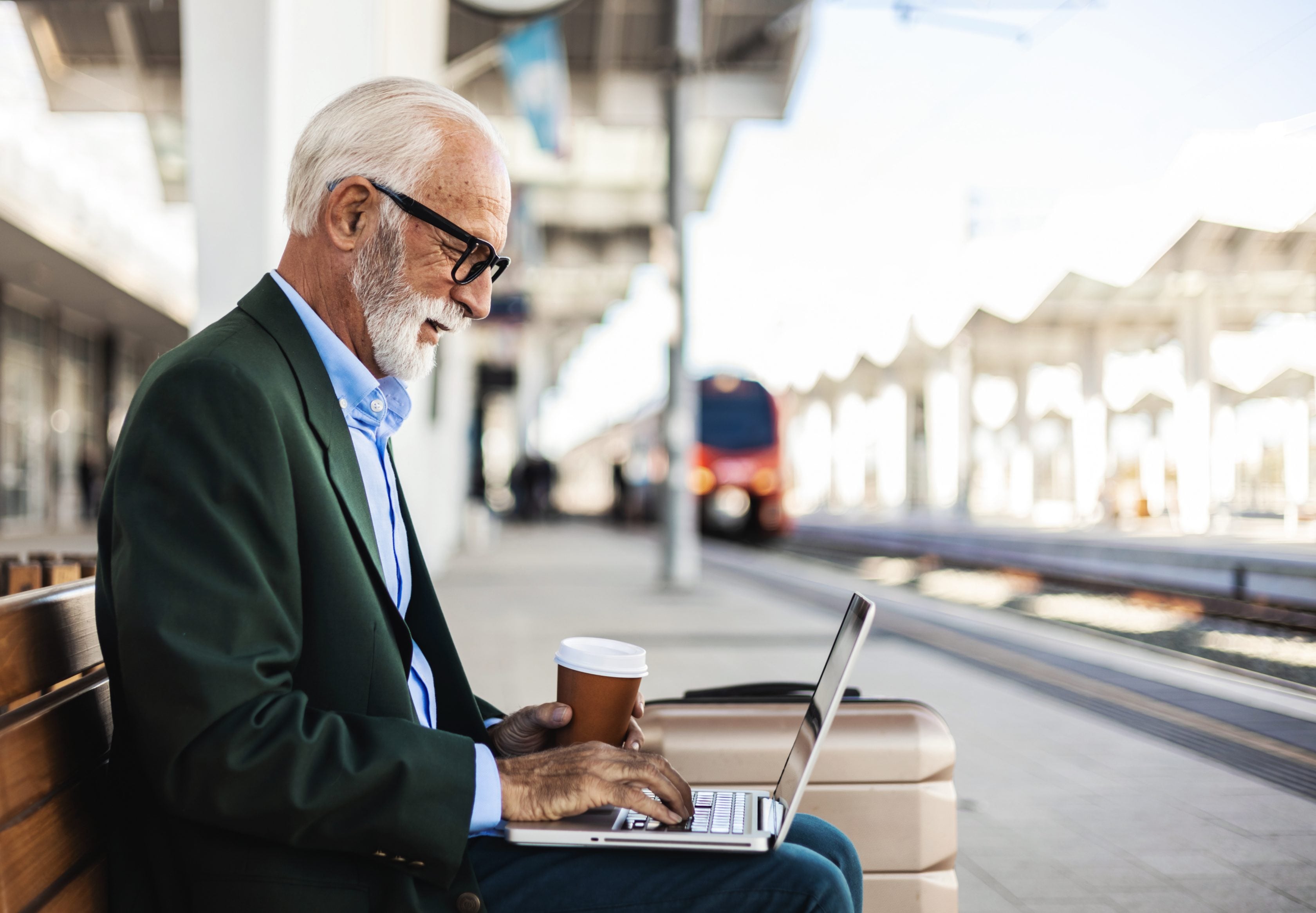 Homme âgé avec son ordinateur portable sur le quai d'une gare
