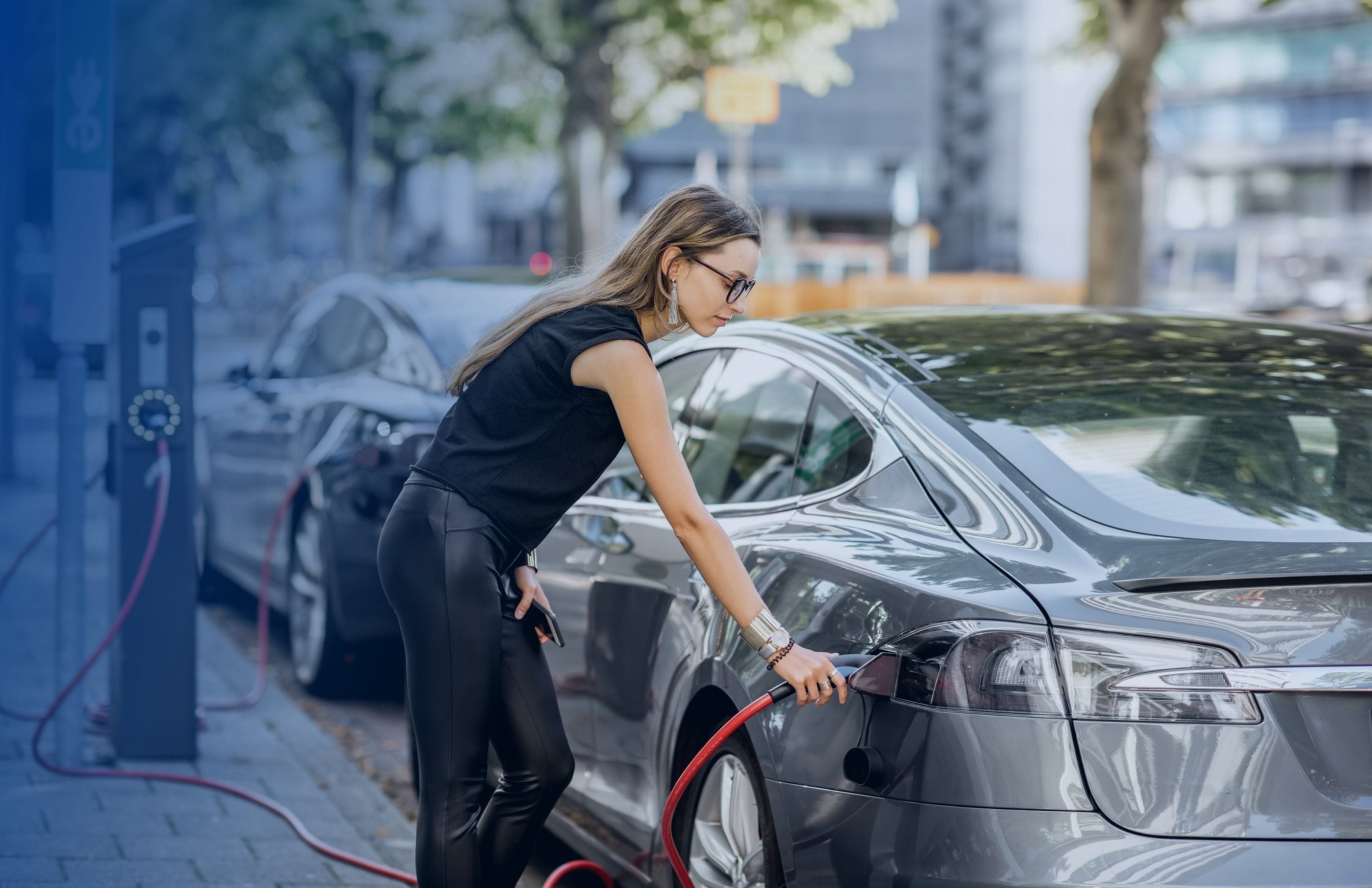 Jeune femme branchant sa voiture électrique à une borne de recharge