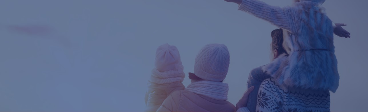 Das Bild ist blau getönt und zeigt eine Familie mit zwei Kindern in Winterkleidung, die den Sonnenuntergang betrachteh. Ein Kind sitzt auf den Schultern des Vaters und ein Kind ist im Arm der Mutter.