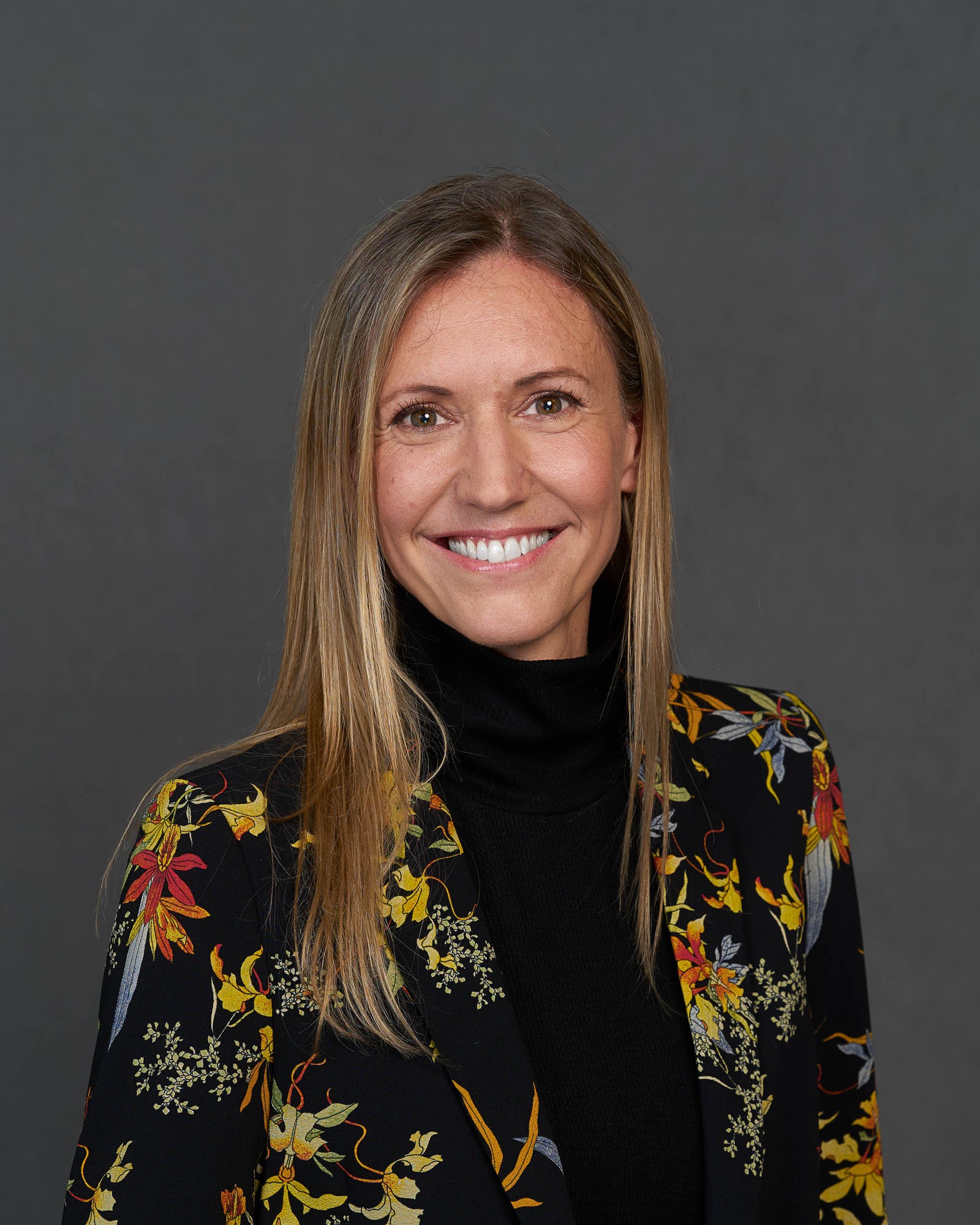 Porträt Beatriz Corti Stuber, Chief Transformation Officer bei Allianz Partners. Frau mit dunkelblondem Haar, schwarzem Blazer mit buten Details und schwarzem Rollkragenpullover.
