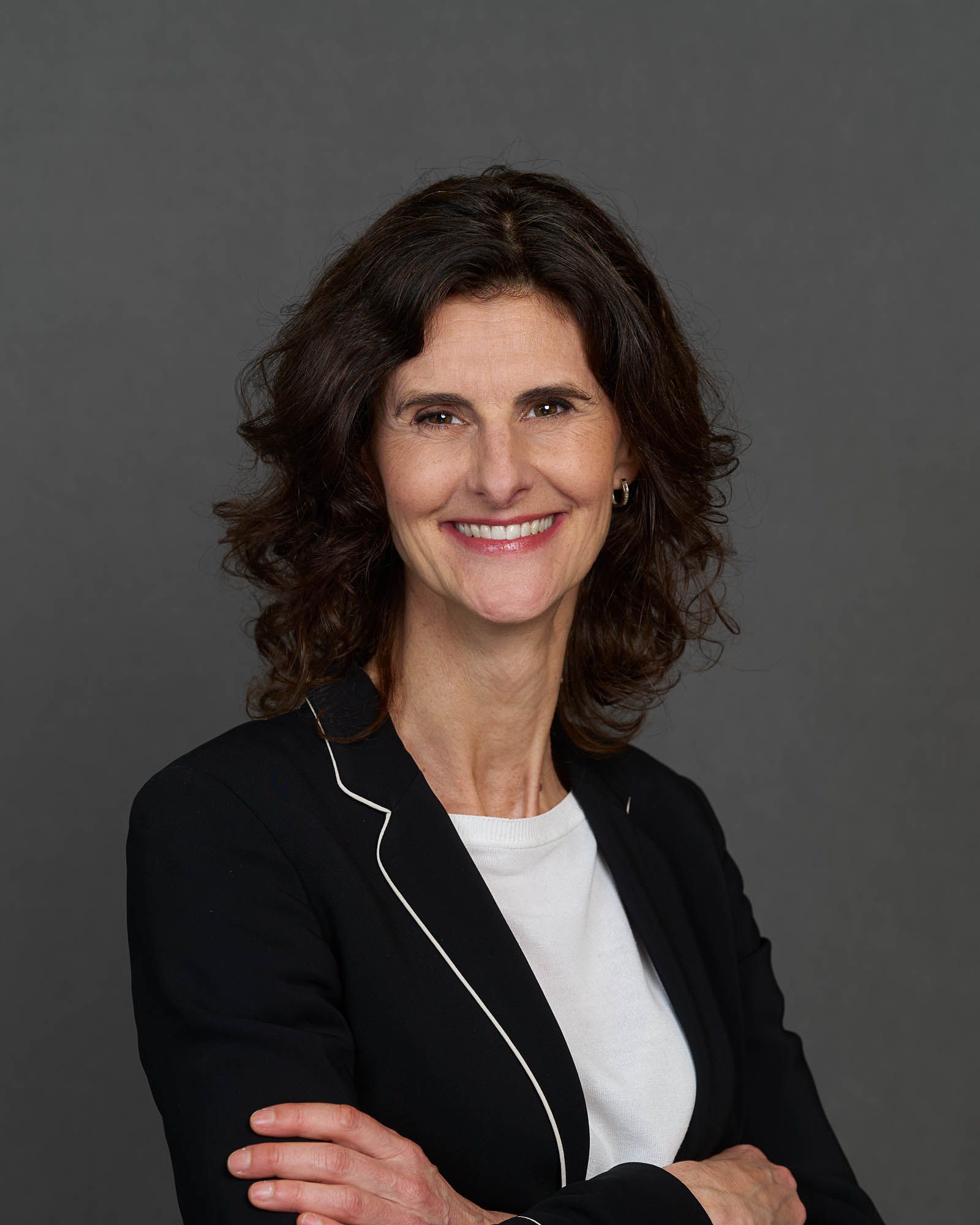 Porträt Anna Kofoed, Chief Officer Travel bei Allianz Partners. Frau mit schwarzem Haar, schwarzem Blazer mit weißen Randdetails und weißem Shirt.